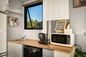 a kitchen with a counter with a microwave and a sink at Rivergum Lodge by Tiny Away in Scotts Creek +9 photos