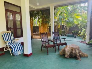a porch with chairs and a table and a tree stump at Arumathi Villa in Bentota
