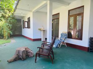 a porch with two chairs and a table and a log at Arumathi Villa in Bentota