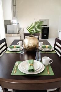 a table with plates and cups and a plant on it at PINK POUI Spaces Vacation Rentals in Arima +16 photos
