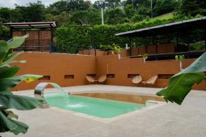 a swimming pool with a water fountain and chairs at Villajesu Villeta in Villeta