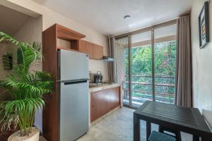 a kitchen with a white refrigerator and a table at Family Studio Suite with Kitchenette & Terrace - Santuario Hotel Boutique in Chemuyil