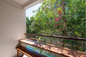 a balcony with a view of a tree with pink flowers at Family Studio Suite with Kitchenette & Terrace - Santuario Hotel Boutique in Chemuyil