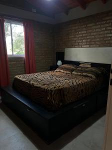a bed in a bedroom with a brick wall at Cabaña Tres linas in Villa General Belgrano +3 photos