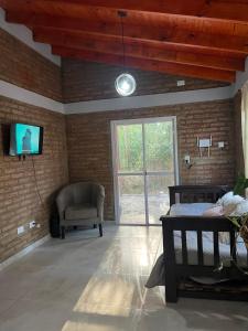 a room with a bed and a tv and a chair at Cabaña Tres linas in Villa General Belgrano