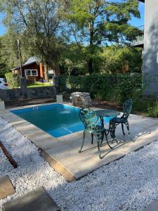 a table and two chairs next to a swimming pool at Cabaña Tres linas in Villa General Belgrano