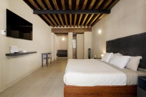 a bedroom with a large white bed and a tv at Colmena Hotel CDMX Centro in Mexico City