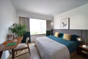 a bedroom with a bed and a table and a desk at basePLUS-Shanghai Binjiang Serviced Apartment in Shanghai
