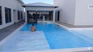 two men sitting in a swimming pool in a building at Dunas beach club in Jaguaruna