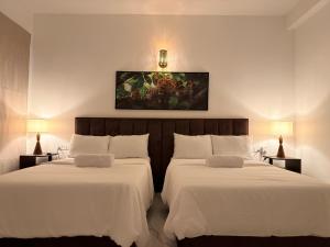 two beds in a hotel room with a painting on the wall at Mount Crest Inn Deniyaya in Deniyaya