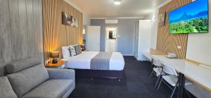 a hotel room with a bed and a flat screen tv at Archer Park Motel in Rockhampton