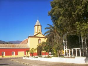 a church with a tower and a red building at Casa La Nuez in Algarrobito