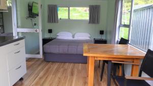 a bedroom with a bed and a table and a desk at Dickson Holiday Park in Thames