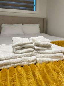 a pile of white towels on a bed at Lizzy cozy Basement suite in Airdrie