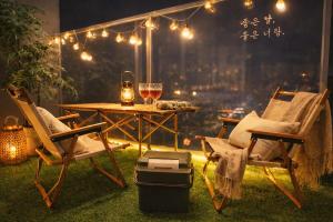 a table and chairs with a glass of wine and lights at Shalom Gold Terrace in Paju