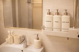 a bathroom with a sink with a mirror and four bottles at Shalom Gold Terrace in Paju +20 photos