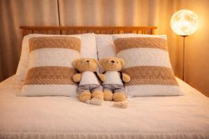 two teddy bears sitting on the pillows on a bed at Shalom Gold Terrace in Paju
