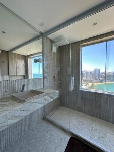 a bathroom with a shower and a sink and a window at Guarapari Center Aparts in Guarapari