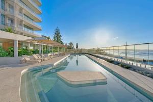 a swimming pool with chairs and umbrellas next to a building at Miles at Kirra Point 604 in Gold Coast