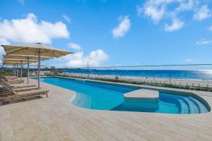 a swimming pool with an umbrella and the beach at Miles at Kirra Point 604 in Gold Coast +15 photos