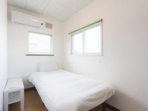 a white room with a bed and two windows at Slow Toya in Lake Toya