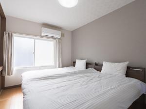 a bedroom with a large white bed with a window at Slow Toya in Lake Toya