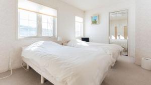 a white bedroom with two beds and a mirror at Pension Himawari in Iizuna +61 photos