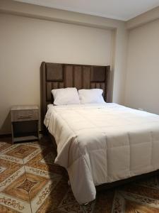 a bedroom with a large bed with a wooden headboard at Allin Samay in Ayacucho