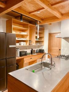 a kitchen with a sink and a stainless steel refrigerator at Ajito Niseko in Kutchan