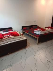 two beds sitting in a room with a white wall at Aakarsh Hotel in Rudraprayāg