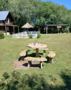 a picnic table and two benches in a field at Del carmen chica in Villa Giardino