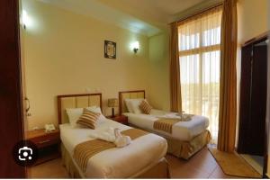 ein Hotelzimmer mit zwei Betten und einem Fenster in der Unterkunft Explore Bahirdar Hotel in Bahir Dar