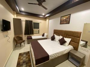 a bedroom with a bed and a chair and a tv at Rudravasa Inn in Varanasi