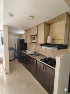a kitchen with wooden cabinets and a stove and refrigerator at Apartamento de 3 habitaciones al Norte de Armenia - excelente ubicación - parqueadero privado in Armenia