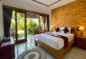 a bedroom with a large bed and a brick wall at Sari Murni in Ubud