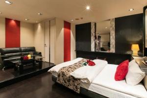 a bedroom with a bed with red pillows and a couch at HOTEL SWING - Couple's Hotel in Beppu