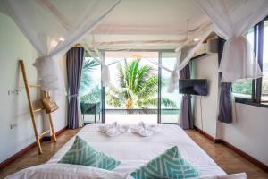 a bedroom with a bed and a large window at The Cozy Beachfront Phuket in Patong Beach
