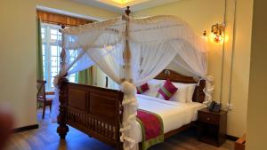 a bedroom with a canopy bed with white curtains at Kingswood Tea Factory in Ramboda