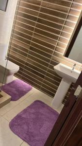 a bathroom with a sink and a toilet and purple mats at chalet - Plumar El Sokhna in Ain Sokhna