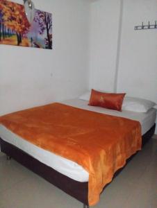 a bedroom with a bed with a orange blanket on it at Hotel Avenida El Bosque a 2 cuadras de la clínica foscal y cardiovascular,HIC,Unab in Floridablanca