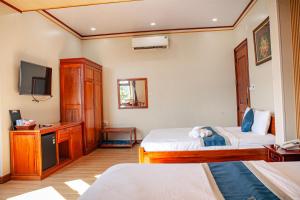 a hotel room with two beds and a television at Nhật Tín Hotel in Kinh Dinh
