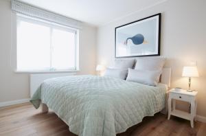 a white bedroom with a bed and two windows at Anker Mal am Hafen in Husum