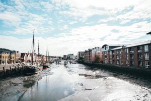 a river with boats in a city with buildings at Anker Mal am Hafen in Husum