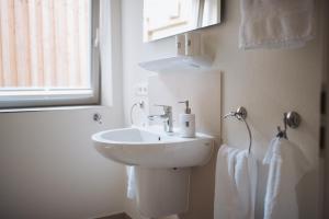 ein weißes Badezimmer mit Waschbecken und Fenster in der Unterkunft Anker Mal Husum Stadt in Husum