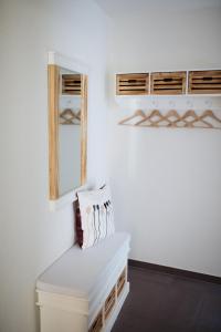 ein weißes Zimmer mit einer Bank und einem Spiegel in der Unterkunft Anker Mal Husum Stadt in Husum