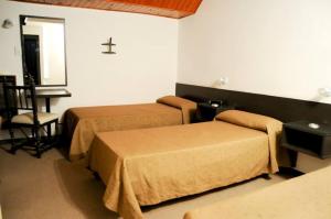 Habitación con 2 camas y una cruz en la pared. en Hotel Alcázar, en Villa María