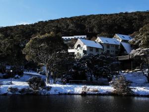 a house in the snow next to a body of water at Boali Lodge Thredbo in Thredbo