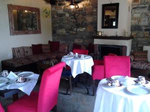 a dining room with two tables and pink chairs at Archontiko Pantou in Portaria