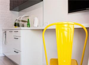 une chaise jaune dans une cuisine avec des armoires blanches dans l'établissement Marszałkowska Apartament 138, à Varsovie