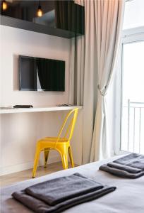 une chambre avec une chaise jaune et une télévision dans l'établissement Marszałkowska Apartament 138, à Varsovie